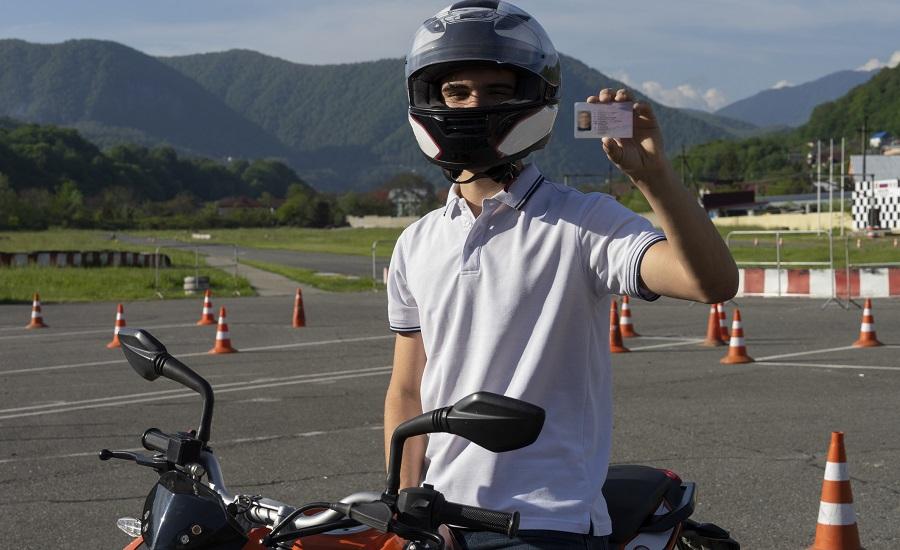 chłopak trzymający prawo jazdy na motocykl
